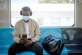 Black businessman travelling alone. A young african american businessman using a cellphone and listening to music on his Royalty Free Stock Photo