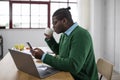 Black Businessman Using Cellphone Working On Laptop Drinking Coffee Indoor Royalty Free Stock Photo