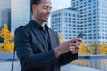 Black businessman using mobile phone app texting outside of office in urban city. Royalty Free Stock Photo