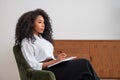 Black businesswoman pensive profile with notebook on lap, office room