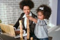 Black businesswoman playing with her children and having fun doing housework