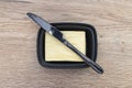 Black butter knife lying on a ceramic butter container, on a wooden table. Royalty Free Stock Photo