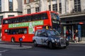 Black cab turning in front of red Double Decker Bus on The Strand, London Royalty Free Stock Photo