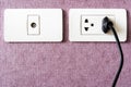 black cable plugged in a white electric outlet mounted on pink w Royalty Free Stock Photo