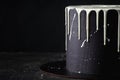 Black cake with white chocolate drips on the black background. Pouring chocolate on the cake. Chocolate drops on the cake