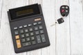 A black calculator with car keys on wood desk Royalty Free Stock Photo