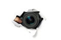 Black camera with a telephoto lens that looks out through a hole in white paper. Concept of paparazzi, espionage, yellow