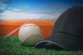 Black cap and a baseball on a green grass with a red running track