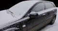 Black car covered with snow in winter Royalty Free Stock Photo