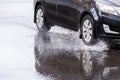 Black car crossing puddle with water splash at daylight closeup with selective focus. Royalty Free Stock Photo