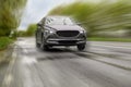 Black car driving at high speed on rainy day outdoors, motion blur effect Royalty Free Stock Photo