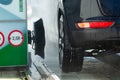 Black car getting washed by an automatic car wash machine on a sunny winter day Royalty Free Stock Photo