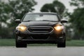 Black Car with lights on in nature on the parking spot. Royalty Free Stock Photo