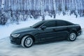 Black car moves in winter on a snowy road Royalty Free Stock Photo