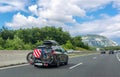 Black car with roof luggage box and trunk bike rack driving on highway. Beautiful mountain landscape background Royalty Free Stock Photo