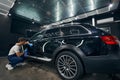 Black car undergoing cleaning procedure in automotive repair shop