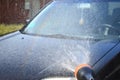 Black car washed with shampoo. Water is pouring onto the car. Rainbow on the water.