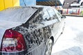 Car in white foam on a manual car wash. Gray car washed in white foam. Car at the car wash Royalty Free Stock Photo