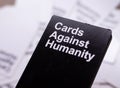 Black Cards against humanity card laying flat on the table with other white blurred cards in the background Royalty Free Stock Photo