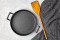 Black cast iron empty frying pan, wooden spatula and gray kitchen towel on a gray concrete background Royalty Free Stock Photo