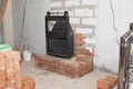 black cast iron firebox with a lift door stands on the brickwork in the living room