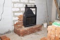 black cast iron firebox with a lift door stands on the brickwork in the living room Royalty Free Stock Photo