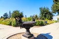 A black cast iron fountain in the garden surrounded by pink and yellow roses with lush green leaves Royalty Free Stock Photo