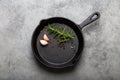 Black cast iron frying pan with rosemary, garlic, pepper top view Royalty Free Stock Photo