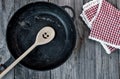 Black cast-iron frying pan with a wooden spoon on a gray wooden Royalty Free Stock Photo