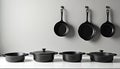 Black cast iron pots and pans displayed neatly on a kitchen wall and shelf. Essential durable cookware for home chefs and Royalty Free Stock Photo