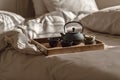 Black cast iron tea pot with herbal tea set up on wood tray on the bed. Royalty Free Stock Photo