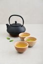 Black cast iron teapot and three ceramic cups of green tea Royalty Free Stock Photo