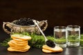 Black caviar served on crackers with vodka and additives