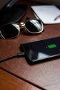 Black cellphone charging on a desk
