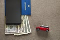 Black cellphone, money American dollars banknotes bills, passport and toy car on copy space background, top view. Travel light, Royalty Free Stock Photo