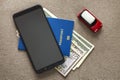 Black cellphone, money American dollars banknotes bills, passport and toy car on copy space background, top view. Travel light, Royalty Free Stock Photo