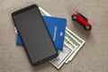 Black cellphone, money American dollars banknotes bills, passport and toy car on copy space background, top view. Travel light, Royalty Free Stock Photo