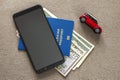 Black cellphone, money American dollars banknotes bills, passport and toy car on copy space background, top view. Travel light, Royalty Free Stock Photo