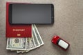 Black cellphone, money American dollars banknotes bills, passport and toy car on copy space background, top view. Travel light, Royalty Free Stock Photo