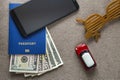 Black cellphone, money American dollars banknotes bills, passport, toy car and funny sunglasses on copy space background, top view
