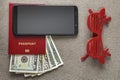 Black cellphone, money American dollars banknotes bills, passport and toy funny sunglasses on copy space background, top view.