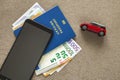 Black cellphone, money euro banknotes bills, passport and toy car on copy space background. Travel light, comfortable journey