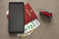 Black cellphone, money euro banknotes bills, passport and toy car on copy space background. Travel light, comfortable journey Royalty Free Stock Photo