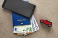 Black cellphone, money euro banknotes bills, passport and toy car on copy space background. Travel light, comfortable journey