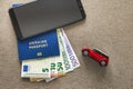Black cellphone, money euro banknotes bills, passport and toy car on copy space background. Travel light, comfortable journey Royalty Free Stock Photo