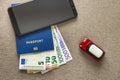 Black cellphone, money euro banknotes bills, passport and toy car on copy space background. Travel light, comfortable journey Royalty Free Stock Photo