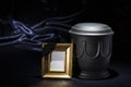 Black cemetery urn with golden mourning frame on dark blue background