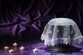 Black cemetery urn with white shroud candles on deep purple background