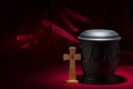 Black cemetery urnk with cross on red background Royalty Free Stock Photo