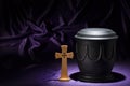 Black cemetery urnk with cross on deep purple background Royalty Free Stock Photo